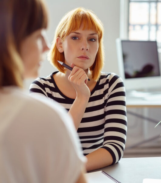 Thoughtful,Young,Redhead,Businesswoman,Watching,Her,Female,Colleague,Waiting,For