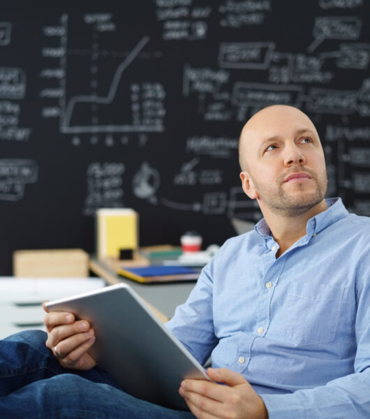 Businessman,Holding,A,Tablet,Looking,Up,In,Thoughts
